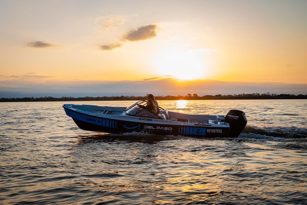 Lancha de Del Paso Fishing navegando el río Paraná al atardecer
