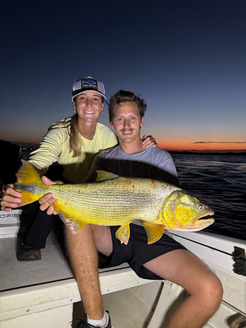 Pareja con un dorado al anochecer