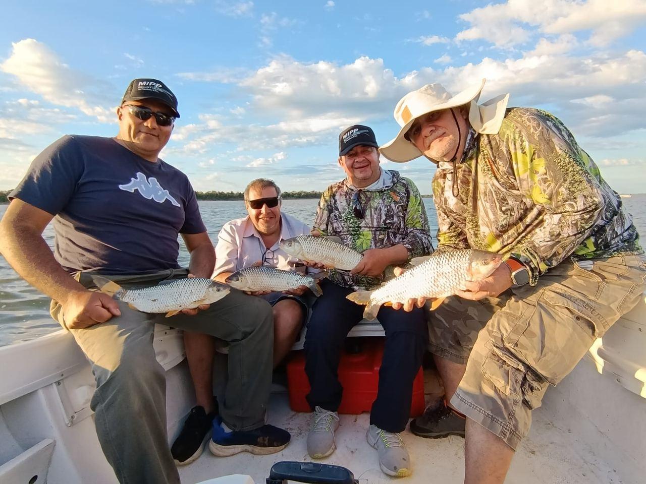 Grupo de pescadores con sus capturas en la lancha