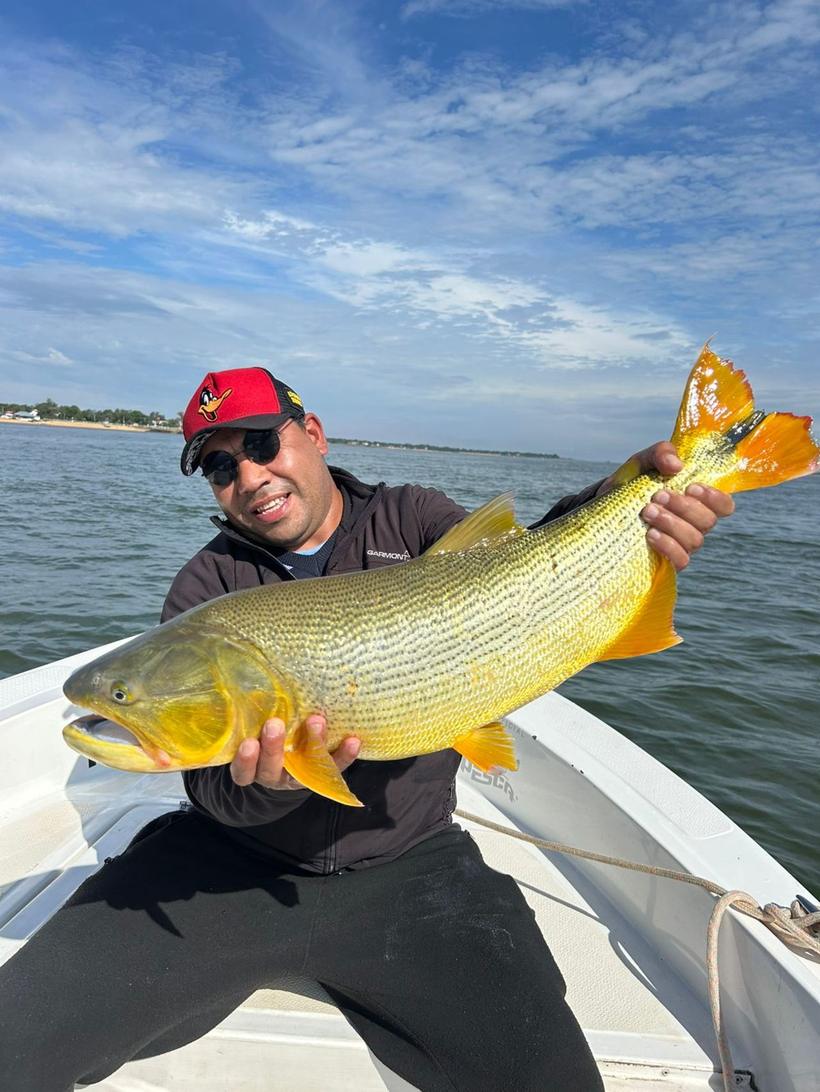 Pescador sosteniendo un dorado en la lancha